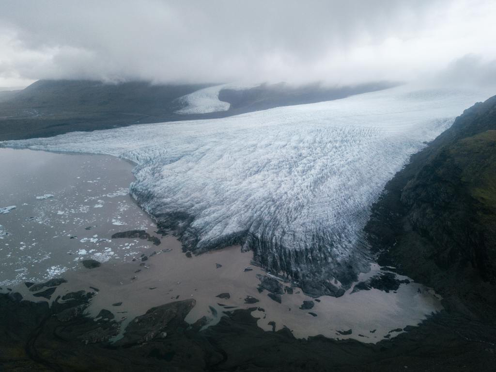 Majestic glacier tongue reaching seashore under gloomy misty sky